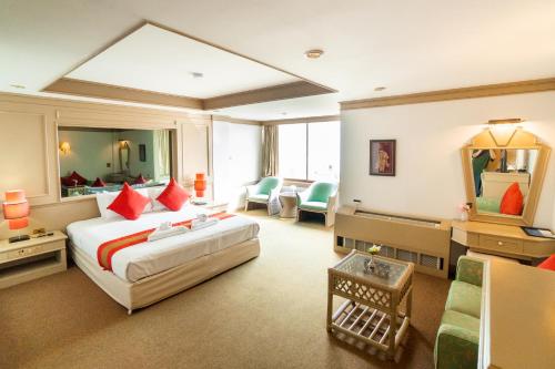 パタヤ・サウスにあるMountain Beach Resortのベッドとリビングルームが備わるホテルルームです。