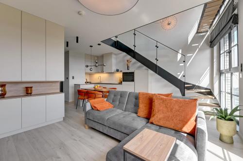 uma sala de estar com um sofá cinzento e uma mesa em Downtown Apartments Dwie Motławy Riverside & Parking em Gdansk