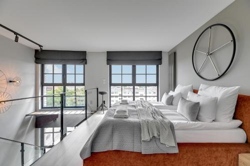 a white bedroom with a large clock on the wall at Downtown Apartments Dwie Motławy Riverside & Parking in Gdańsk