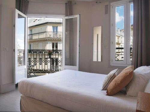 une chambre avec un grand lit blanc et un balcon dans l'établissement Bonséjour Montmartre, à Paris