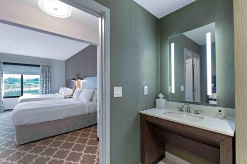 a bedroom with a bed and a bathroom with a sink at Residence Inn by Marriott Atlanta Covington in Covington