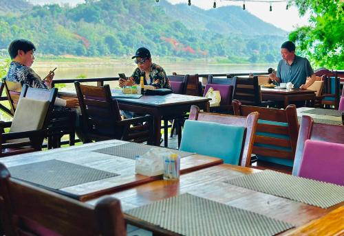 a group of people sitting at tables in a restaurant at Villa Phonethip Mekong Riverside in Luang Prabang