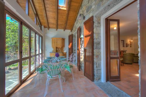 a dining room with a table and chairs and windows at Villa Il Castagno Few Min From Beach - Happy Rentals in Castelveccana