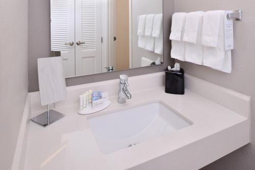 a white bathroom with a sink and a mirror at Courtyard Beaumont in Beaumont