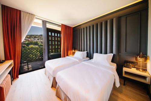 two beds in a hotel room with a large window at Sandali Metekhi Boutique Hotel in Tbilisi City