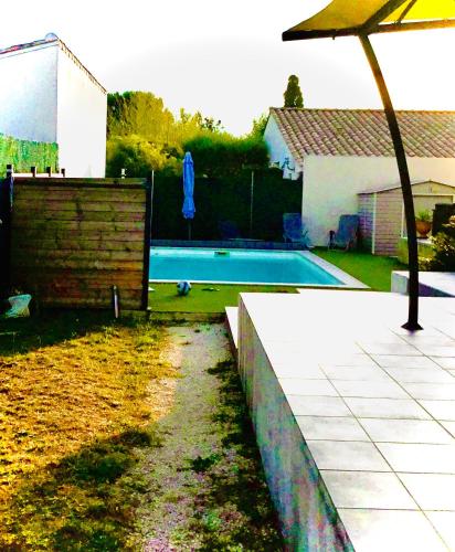 une cour avec une piscine et un parasol dans l'établissement Villa moderne piscine privée calme soleil près de Nîmes, à Clarensac