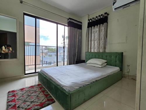 a bedroom with a green bed and a large window at Vintage GreyRoom - Family Stay in Dhaka