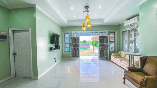 sala de estar con paredes verdes, sofá y TV en พูลวิลล่าชะอำ Amazia Pool Villa, en Cha Am