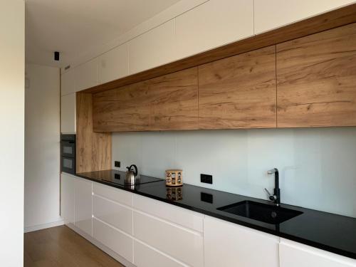 a kitchen with white cabinets and a black counter top at Dunajec Home in Chełmiec