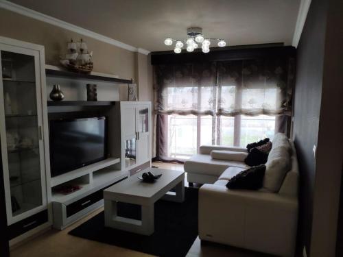 uma sala de estar com um sofá e uma televisão em Precioso Piso+Garaje Zona Sanxenxo Grove Portovono em Pontevedra