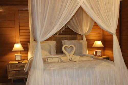 a bed with a white canopy with a heart on it at Green Village Jungle Resort in Nusa Penida