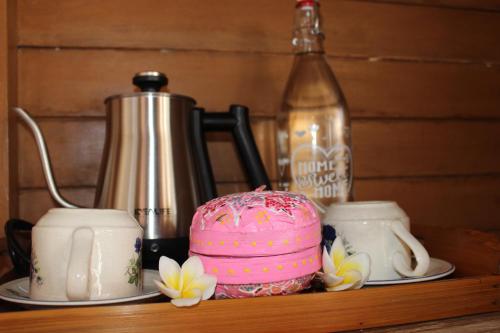 a pink cake sitting on a shelf with two cups at Green Village Jungle Resort in Nusa Penida