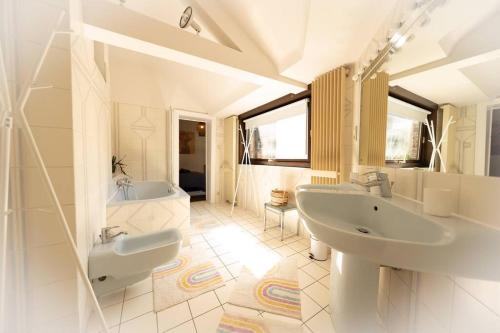 een witte badkamer met 2 wastafels en een bad bij Camelia, un charme Montois in Bergen
