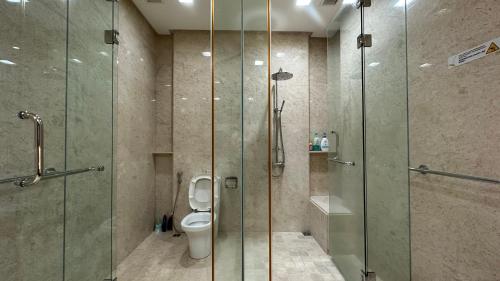 a bathroom with a glass shower and a toilet at Cozy Straits Quay Seafront Suite in Tanjong Tokong