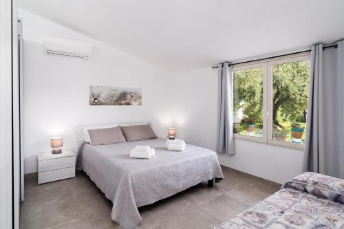 a white bedroom with a bed and a window at Domo Bonaeras in Irgoli