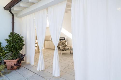 a patio with white curtains and a table at Domo Bonaeras in Irgoli