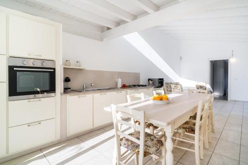 a kitchen with white cabinets and a white table and chairs at Domo Bonaeras in Irgoli