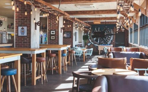 a restaurant with tables and chairs and a brick wall at Hafan y Môr Holiday Park in Pwllheli