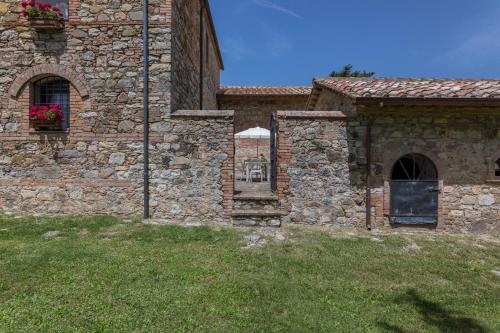 a stone building with a door and a grass yard at Agriturismo Spazzavento in Palazzone