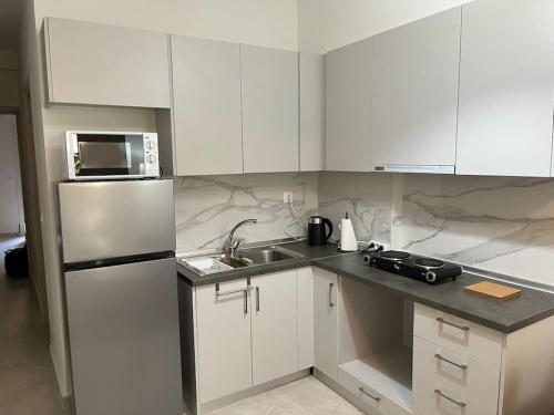 una cucina con armadi bianchi e frigorifero in acciaio inossidabile di Amazing apartment in the center a Salonicco