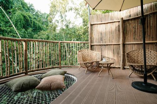 a porch with chairs and an umbrella on a deck at Treehouse de Valentine in Balamban