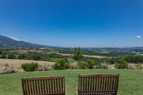 two wooden benches sitting on top of a grassy hill at Agriturismo Spazzavento in Palazzone