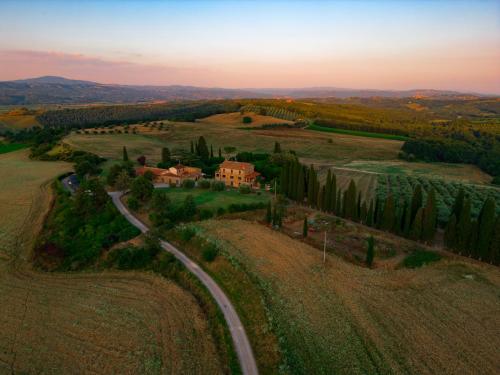 a house in the middle of a field with a road at Agriturismo Spazzavento in Palazzone