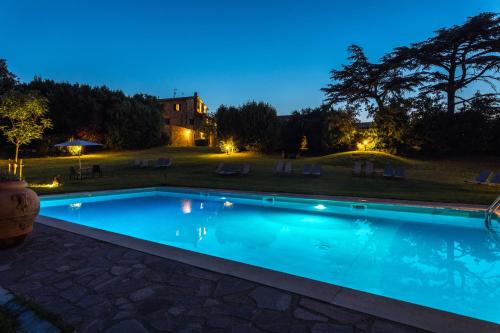 a swimming pool at night with a house in the background at Agriturismo Spazzavento in Palazzone