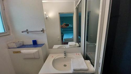 ein Bad mit einem Waschbecken und einem Spiegel in der Unterkunft Hôtel Bel Valen in Le Val