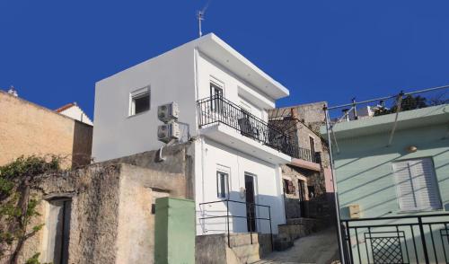 a white building with a balcony on a street at Maisonette Kavousi with Mountain and Village View in Kavoúsion