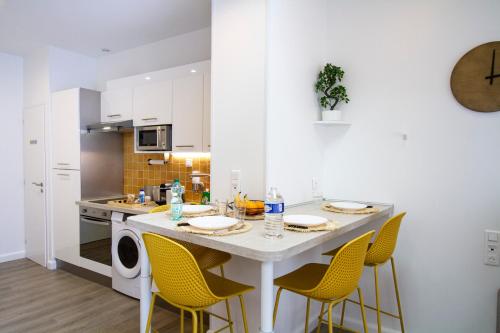 a kitchen with a large white island with yellow chairs at Soleil d'Été - Netflix & Wifi - Balcon - Parking Gratuit - check-in 24H24 - GoodMarning in Châlons-en-Champagne