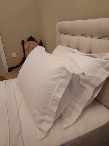an unmade bed with white sheets and pillows at Valia's house -Makri Village in Mákri