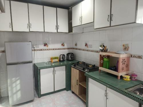 una cocina con armarios blancos y encimeras verdes en NAURAH HOMESTAY, en Sungai Petani
