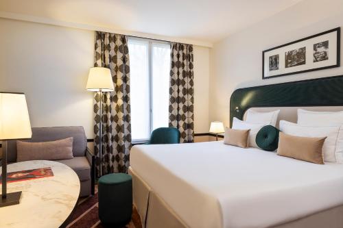 a hotel room with a large bed and a chair at Hôtel Aiglon in Paris