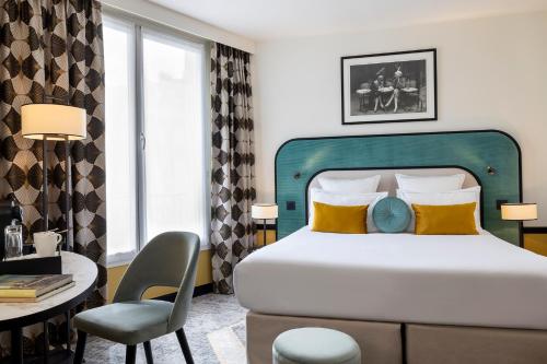 a bedroom with a bed and a desk and a chair at Hôtel Aiglon in Paris