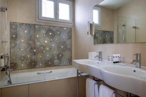 a bathroom with two sinks and a tub and a mirror at Hôtel Aiglon in Paris