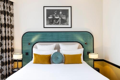 a bed with a green headboard and yellow pillows at Hôtel Aiglon in Paris