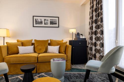 a living room with a yellow couch and chairs at Hôtel Aiglon in Paris