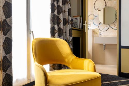a yellow chair in a room with a window at Hôtel Aiglon in Paris