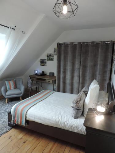 een slaapkamer met een bed, een stoel en een bureau bij Relais Du Boss in Saint-Vran