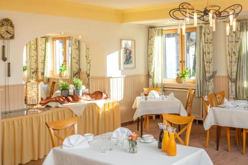 Un comedor con mesas y un perro acostado en la mesa. en Hotel Das Bayerwald, en Lam