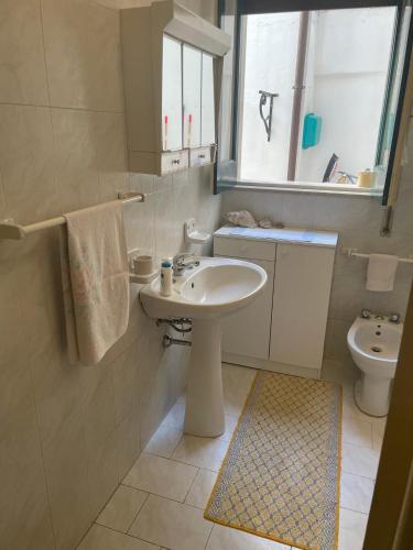 a bathroom with a sink and a toilet and a window at Casa della nonna Marina in Floridia