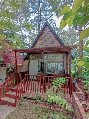a small house with a red deck in the woods at Pijar Resort Powered by Cocotel in Kudus