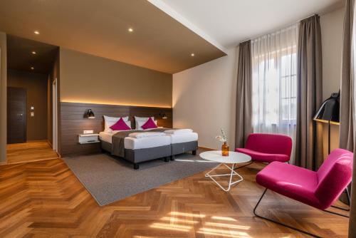een slaapkamer met een bed en een tafel en stoelen bij Müller! Das Weingut & Weinhotel in Hammelburg