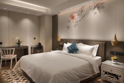 a bedroom with a large white bed and a chair at Paco Hotel Dongpu Guanghzou -Free Shuttle Bus for Canton Fair in Guangzhou