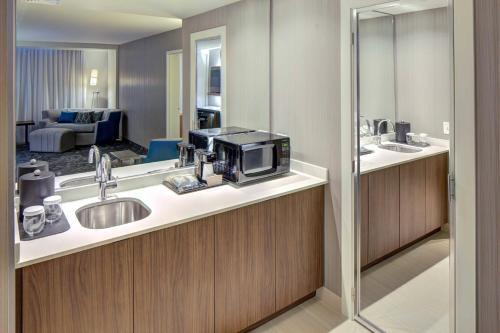 a bathroom with a sink and a living room at Courtyard by Marriott Appleton Riverfront in Appleton