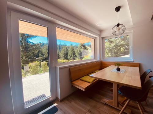 a dining room with a table and two windows at NORDIC Apartamente Păltiniș in Păltiniş