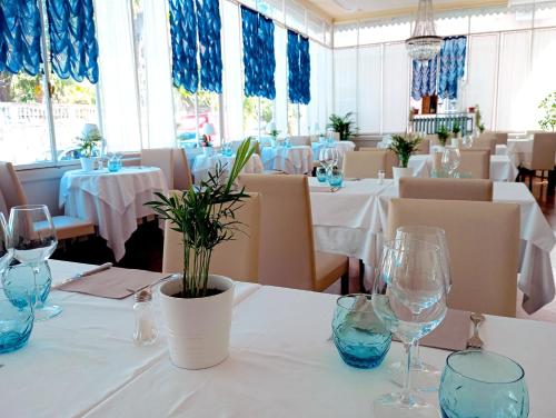 una sala da pranzo con tavoli bianchi e bicchieri blu di Hotel Morandi a Sanremo