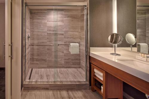 a bathroom with a shower with a sink and a mirror at Courtyard by Marriott Philadelphia City Avenue in Philadelphia