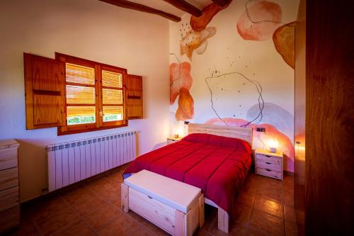 1 dormitorio con 1 cama con manta roja en Masia Cal Magi, en Font-Rubí